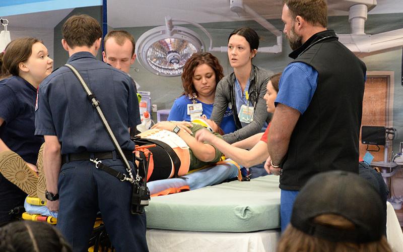 Dr. Chris Bell, right, directed the trauma team treating the teenage victim of a car crash during the Safe Driving Summit at Fannin County High School. Bell, MD, FACS, is with University Surgical Associates with Erlanger Medical Center. Those making up the team included Whitley McDaris, fourth from right, Emergency Department manager at Blue Ridge Medical Center, and Emily Parker, RN, CCRN, from Erlanger Medical Center who was the patient.