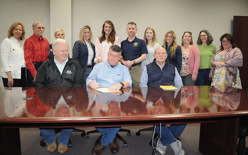 News Observer Photo/Jackson Elliott Fannin County Commission Chairman Jamie Hensley signs a National Crime Victims’ Rights Week proclamation. Those attending the event included various representatives of District Attorney Frank Wood’s office including those working in the Victim Services program. Shown during the proclamation signing are, from left, front row: commissioners Johnny Scearce, Hensley, and Glenn Patterson; and, back row, Joan Rutledge, Ferrell Yates, Carmen Yates, Marianne Gelakoska, Anna Poste