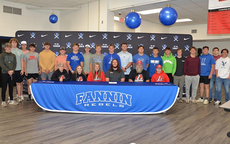 Rebel football player Jacob Dye, seated, center, committed to further his football career with LaGrange College Monday, April 7. Dye is shown surrounded family, peers and teammates during the signing ceremony held in the cafeteria at Fannin County High School.