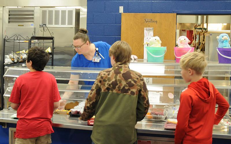 Carrie Couch assists students during lunch at Blue Ridge Elementary School. While television and radio reports have warned of cuts affecting many programs, the National School Lunch Program is not affected by those cuts.