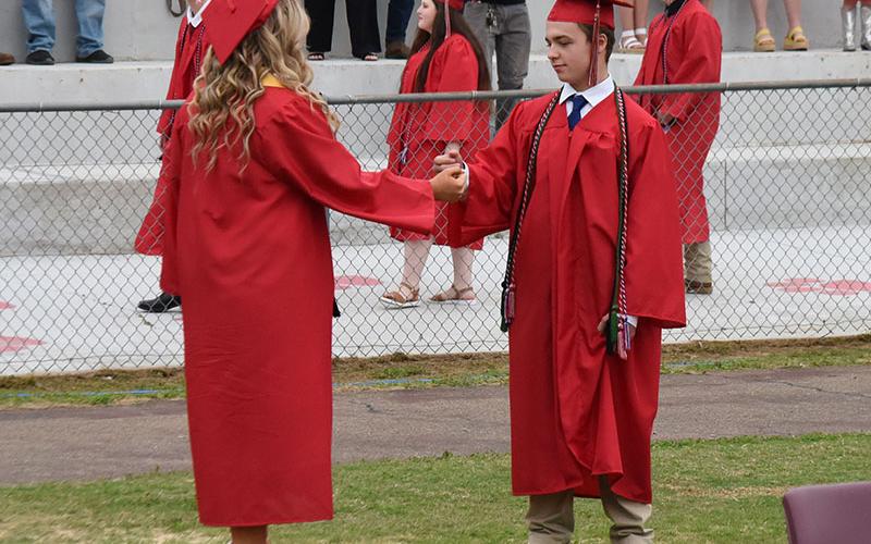 Kenzlie Ballew, left, and Noah Thompson perform a ceremonial goodbye handshake at the beginning of the Copper Basin High School graduation ceremony.