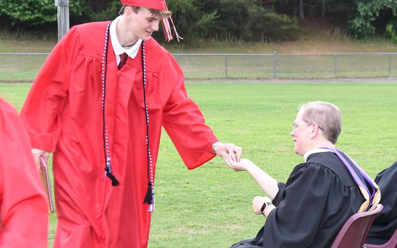 Thatcher McWhorter passes the ceremonial token to Anita Pippin after accepting his diploma from Polk County Director of Schools Dr. James Jones. McWhorter was one of 32 Copper Basin High School graduates.