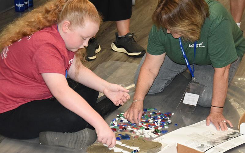 Elissa Robertson gets help decorating her memory stone from Lisa Garrison.