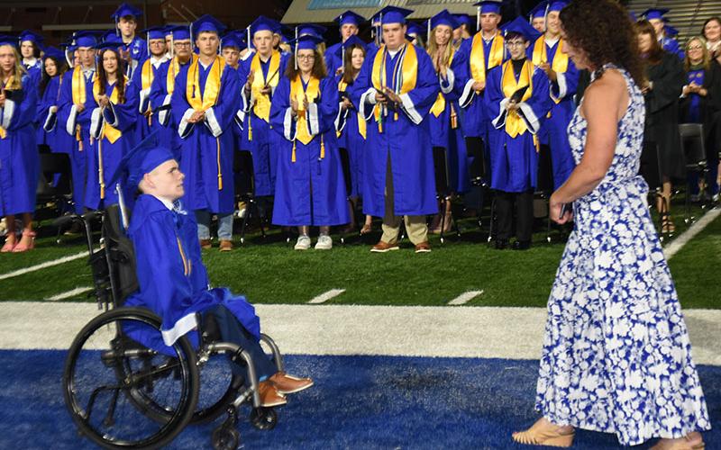 Fannin County High School graduates stood, clapped and cheered as Brady Smith made his way along the football field sideline to receive his diploma. He was greeted by his mother, Ashley H. Weeks, just before reaching school officials waiting to congratulate him.