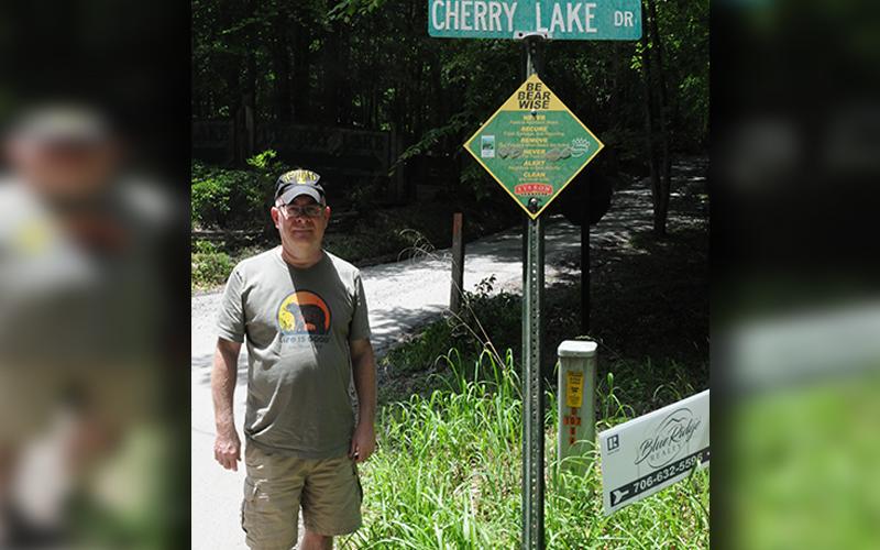 Gerald Hodge stands near a sign giving advice on how to stay safe around bears.
