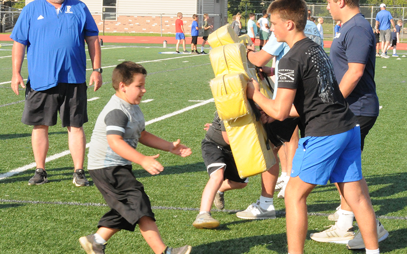 Fannin County Rebel Coach Adam Turner, left, watches as students train during Youth Football Camp. The camp was held last Tuesday night, July 8, on the high school football field.