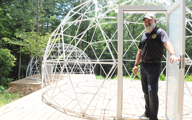 Tim Doherty, owner of Doc’s Healing Hives, opens the door to a geodesic dome under construction.