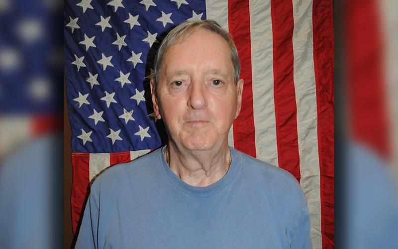 Danny Drake stands before the American flag that once flew over the USS Macdonough.