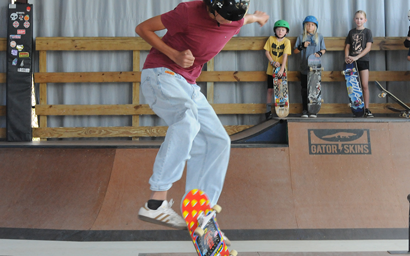 Jayden Henderson catches air while flipping a skateboard.