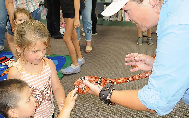 Children reach out to touch a milk snake held by Wildlife Interpretative Specialist Kathy Church.