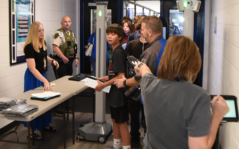 Dawn Heaton, back to camera, alerts school officials to a problem detected by the new weapons detection system at Fannin County High School. No weapons were found when students were checked for the first time last Wednesday morning. In the case above, as was true in many instances, the system alerted on binders that had been left in backpacks. Because backpacks are clear, they did not have to be emptied for school officials to determine the problem.