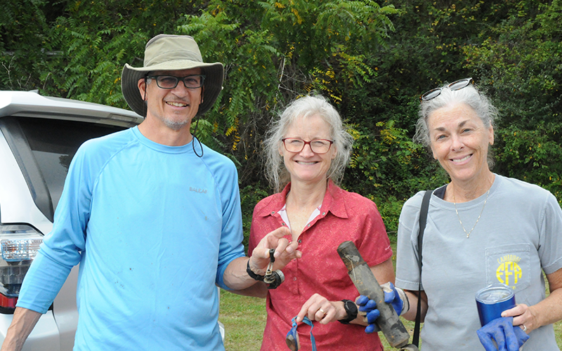 Leigh Maloney, left, holds a shock absorber found during the Rivers Alive cleanup along the Toccoa River in Blue Ridge. With Maloney are Parry and Donna Ruder.