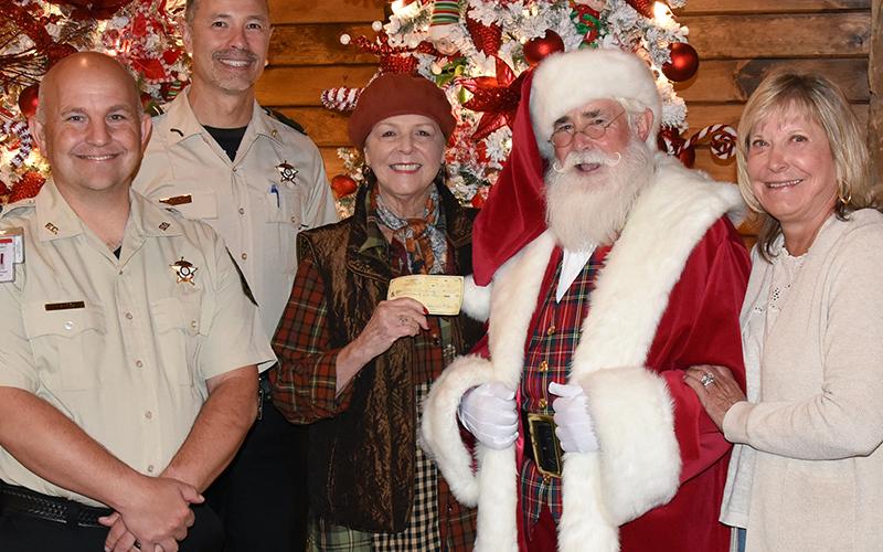 Renee Roberts presented a $1,000 donation during the Tour of Trees at Serenity in the Mountains to be used for the Fannin County Sheriff’s Office Shop With A Cop program. Roberts is an annual contributor to the event, one of many who help make it successful. Shown accepting Roberts’ donation are, from left, deputy sheriff School Resource Officer Tommy Shook, Captain Darvin Couch, Roberts, Santa Claus during his special, early season visit, and Serenity owner Linda Cole.