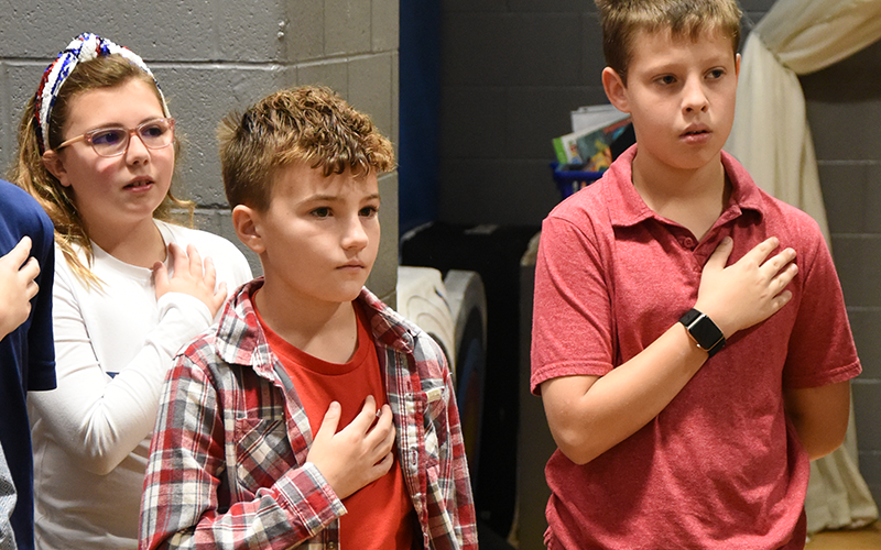 Ryleigh Callihan, Hudson Franklin, and Jasper Evans say the Pledge of Allegiance during the Veterans Day ceremony at Blue Ridge Elementary School.