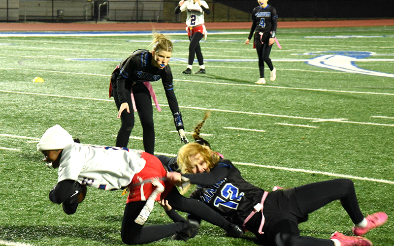 Lady Rebel footballer Adia Galloway (#12) dives on the ground to reach the flag of a Mays County player in the Fannin high flag football state playoff game at home December 4. Jordan Golden is there to assist. Karli Says (#4) is in the background. Fannin defeated Mays to advance to the Sweet 16 game later that evening.