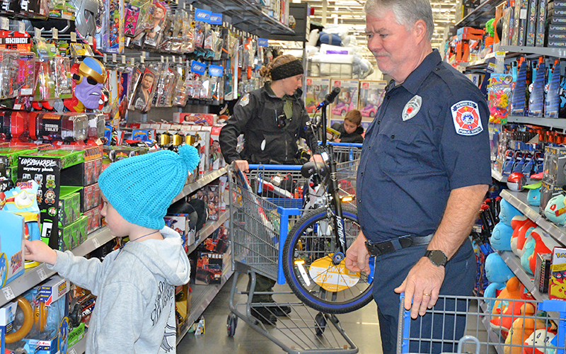 Jeff Jones with the Fannin County Emergency Management Agency helps a child shop during Shop With A Cop December 13.