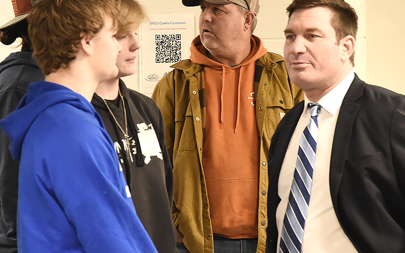 Coach David Nichols visited with Cash Ades, left, and Cash Cochran Thursday night before meeting with community members.