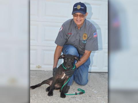 Animal Control Officer Pat Patterson kneels next to this cute, black female puppy thought to be a lab/bull mix. She was picked up October 2 on Weaver Street in McCaysville. She is sweet and playful and needs a family to love her and provide for her. Could that be you? View this cutie pie pup under Animal Control number 299-19.