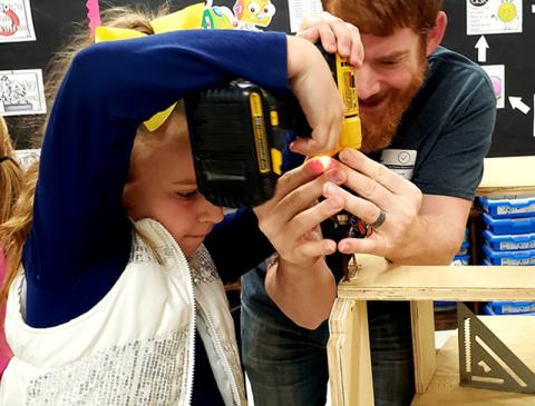 East Fannin student Vera Grace Price concentrates as she drills a hole for a racer that will be entered in the Blue Ridge Soap Box Derby. Helping her is event organizer Mike Sullivan.