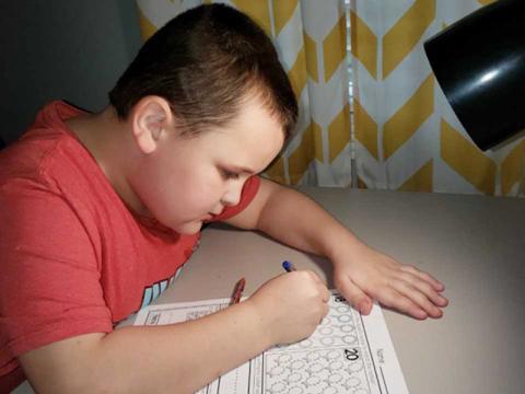 Blue Ridge Elementary School student Izaiah Bradburn works diligently at home to complete his school work while school is out.