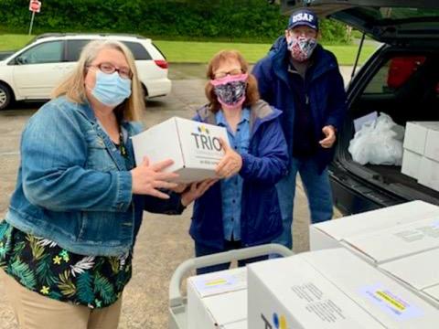 Meals on Wheels Coordinator Pam Godfrey, left, is shown passing off a box to Feed Fannin volunteer Brenda McKee. The boxes are filled with meals that were delivered to homebound seniors around Fannin County. Charlie McKee is shown in the background waiting for another box.