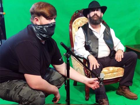 Boom operator Jackson Phillips checks the audio levels while Blue Ridge Community Theater President of Main Stage Michael Lacy sits before the green screen before filming.