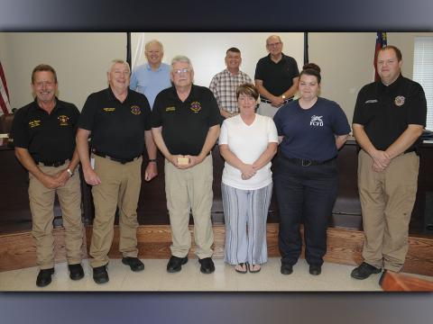 Darrell Payne was honored at the Fannin County Board of Commissioners meeting Tuesday, June 23, when he officially announced his retirement after 38 years with the county Emergency Medical Service. Shown after Payne was presented a gift are, from left, front, Fire Chief Larry Thomas, Emergency Management Agency Director Robert Graham, Payne and his wife Tammy, new EMS Director Becky Huffman, outgoing 911 Director Patrick Cooke, and, back, Post 1 Commissioner Johnny Scearce, Commission Chairman Jamie Hensley