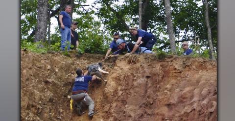 Fannin County Emergency Management Agency (EMA) Firefighter Corey Shaw pushes Finn to safety while EMA Communications Officer John Reel, Firefighter Channing Johnstone, Firefighter/First Responder Virginia Jones, Firefighter Brad Beavers, EMA Deputy Director Patrick Cooke and an individual with Evolutionary K9 help from above.