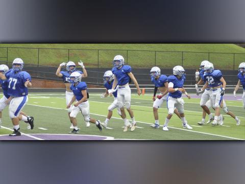 The Fannin County Rebel football team hypes up the crowd as they run out on the field at the start of their scrimmage game against Gilmer County Friday, August 6.