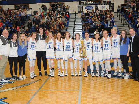 The Fannin County Lady Rebels proudly displayed the Region 7AA Championship trophy after their win over Chattooga High School Friday night. Shown following the team’s 24th victory this year are, from left, assistant coach Randy Hallmark, assistant coach Lacy Walden, Nicole Pittman, Macy Hawkins, assistant coach Megan Norton, Ellie Cook, Reigan O’Neal, Riley Reeves, Courtney Davis, Becca Ledford, Jenna Young, Reagan York, Ava Queen, Jayden Bailey and head coach Ryan Chastain.