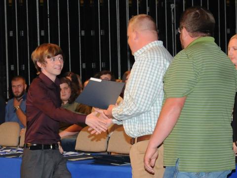 Dallas Trent Lowery is all smiles as he is presented a David Curtis Memorial Scholarship to fund his education as an emergency medical technician. Curtis’ sons, Josh, presenting the award, and Matt, attended Fannin County High School Awards Day to present the scholarship.