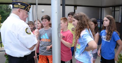Gerald “Chief Mac” McMillan, left,  demonstrated the proper way to raise and lower the American flag for this group of students at Blue Ridge Elementary School.
