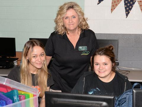 Mountain Education Charter High School (MECHS) Principal Vicky Henry, standing, is shown helping Twyla Benefield (left) and Mattie Coffee during a class at the Blue Ridge campus.