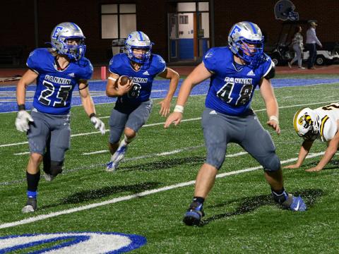 Corbin Davenport (8) runs the ball behind teammates Carson Callihan (25) and Baylor Twiggs (48) as they clear the way in recent action for the Rebels.