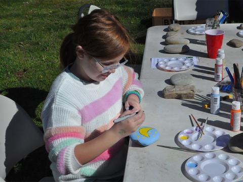 Ruby Shults was excited to tour Project Chimps Saturday. While waiting she painted a banana on a rock at the tables set up for rock decorating. 