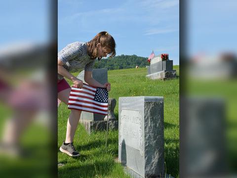 Valerie French places a flag at a veteran’s headstone in J.P. Chastain Memorial Park.