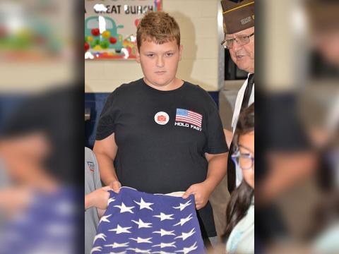  Izaiah Bradburn listens closely to instructions from Honor Guard member Richard Crosley on how to properly fold a U.S. flag.