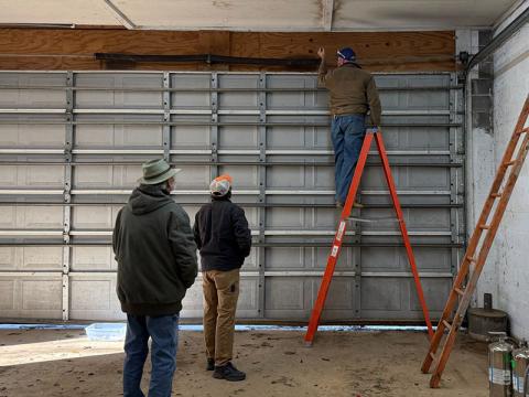Polk County Executive Robby Hatcher, on ladder, works on the door at Fire Station 5. Also shown are David Farrow and Ben Brannam.