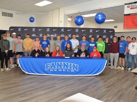 Rebel football player Jacob Dye, seated, center, committed to further his football career with LaGrange College Monday, April 7. Dye is shown surrounded family, peers and teammates during the signing ceremony held in the cafeteria at Fannin County High School.