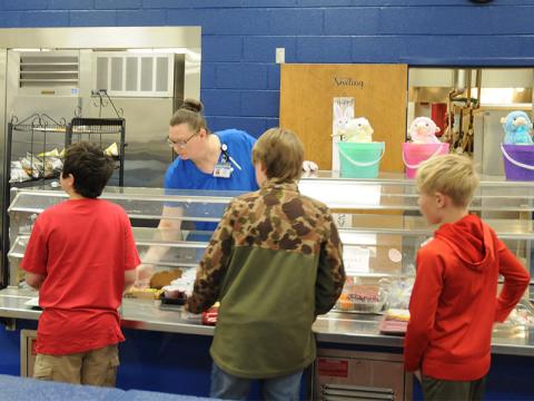 Carrie Couch assists students during lunch at Blue Ridge Elementary School. While television and radio reports have warned of cuts affecting many programs, the National School Lunch Program is not affected by those cuts.