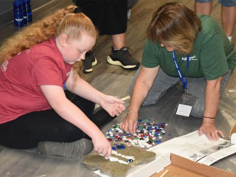 Elissa Robertson gets help decorating her memory stone from Lisa Garrison.
