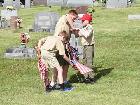 Boy Scouts from Troop 32 Max Benson, Grant Dilbeck and Ethan Threet, from left, honor a veteran by putting a flag on his grave in Crestlawn Cemetery.