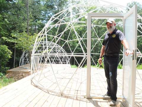 Tim Doherty, owner of Doc’s Healing Hives, opens the door to a geodesic dome under construction.