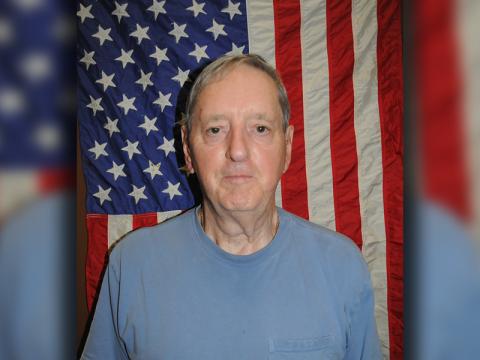 Danny Drake stands before the American flag that once flew over the USS Macdonough.