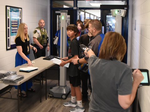 Dawn Heaton, back to camera, alerts school officials to a problem detected by the new weapons detection system at Fannin County High School. No weapons were found when students were checked for the first time last Wednesday morning. In the case above, as was true in many instances, the system alerted on binders that had been left in backpacks. Because backpacks are clear, they did not have to be emptied for school officials to determine the problem.