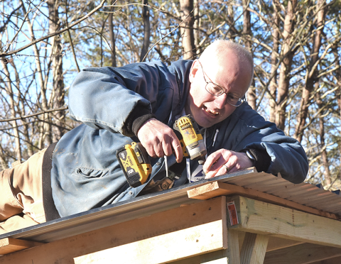 Freedom for Fido Co-Founder Fritz Gilbert secures the metal for a covered awning the volunteers built at their 200th fence build for the dog, Kie, to take shelter from rain and weather.  
