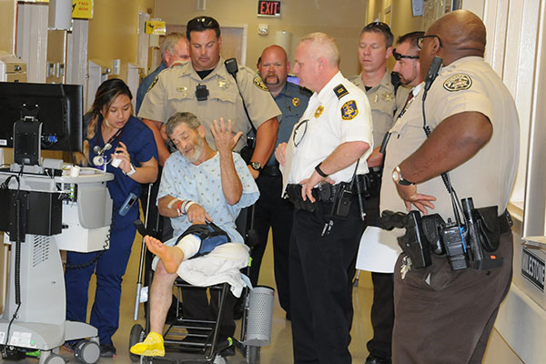 Deputies from the Cobb County Sheriff’s Office served warrants on James Larry Parris Jr., (in chair) before turning him over to McCaysville police officers shortly before noon Thursday. Shown with the Cobb County deputies as Parris is taken from WellStar Kennestone Hospital are McCaysville Patrolman Pete Kusek (in background), McCaysville Patrolman Mark Chastain, McCaysville Det. Capt. Billy Brackett, and McCaysville Police Chief Michael Earley.Law enforcement officers prepare to put James Larry Parris Jr.,