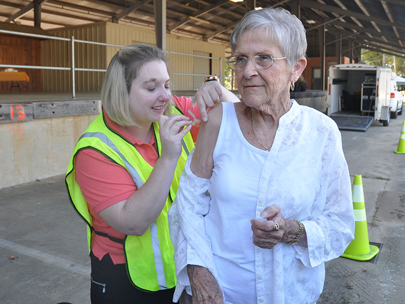 Carole Patterson stands stoic for her flu shot given by Immunization Coordinator Ashley Deverell. A drive-by flu shot clinic and mass medication drill was held at the old State Farmers Market in Blue Ridge October 3.