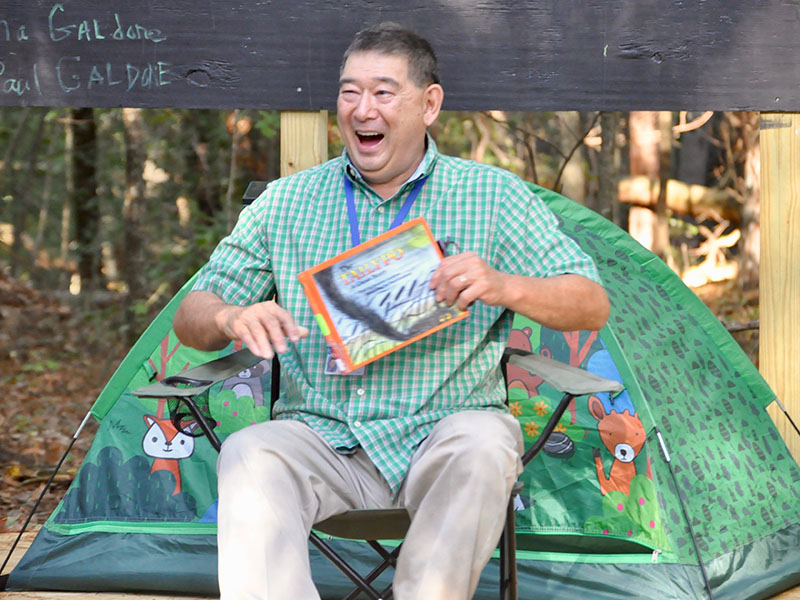 East Fannin Elementary School Media Specialist Gary Baxter read to students and their families at the new outdoor classroom during the school’s camping themed literacy night.