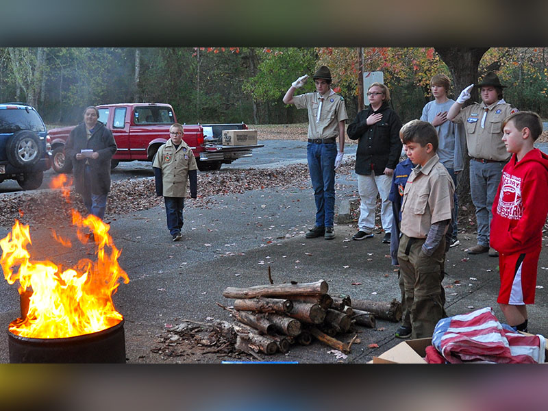 Ducktown Boy Scouts and Cub Scouts pay their respects as the last bits of an old American flag are retired the evening of Saturday, November 9.